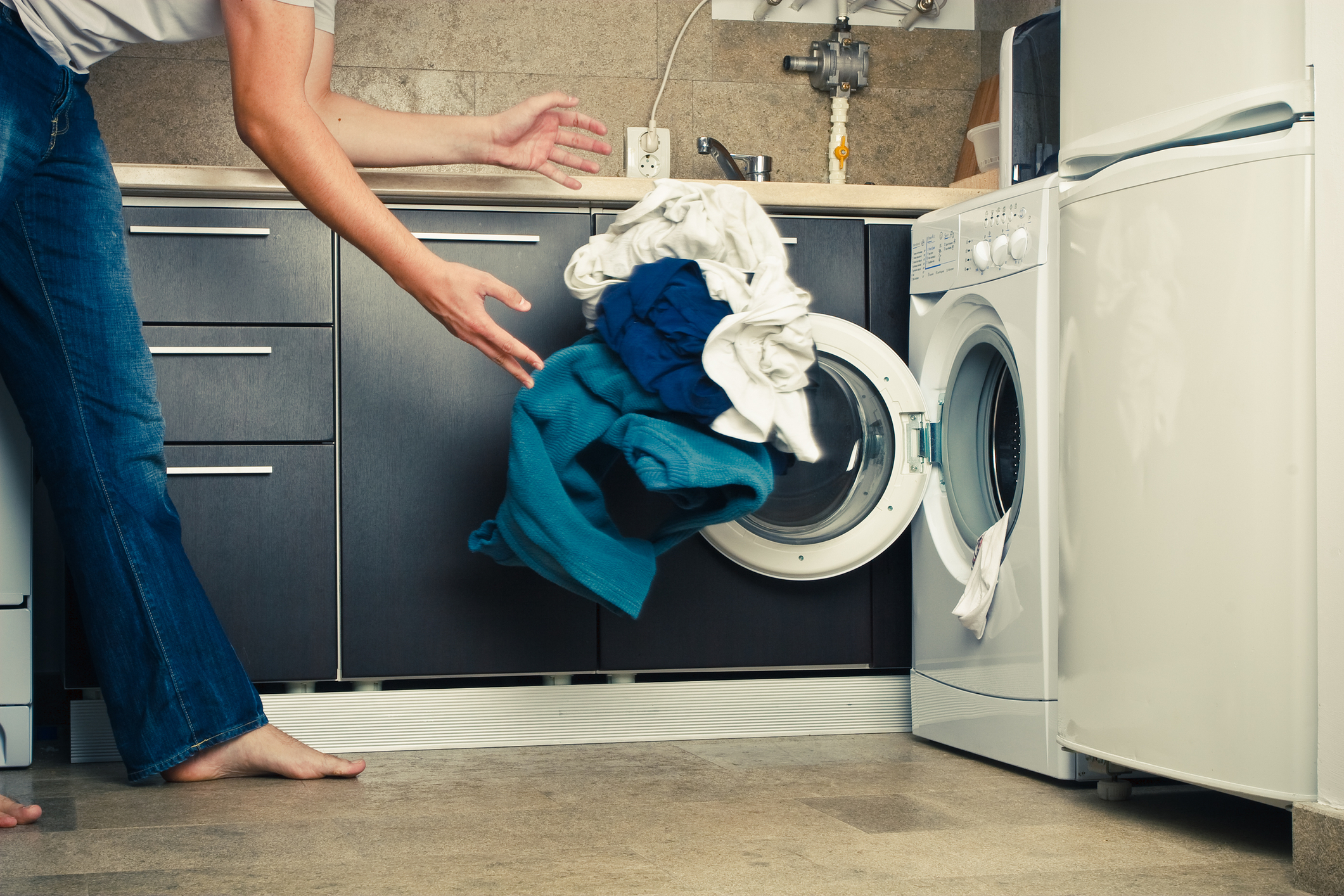 Distinctive man throwing clothes into washing machine