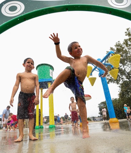 Kids jump through the Sprays of Water at the Greenwood Splash Park