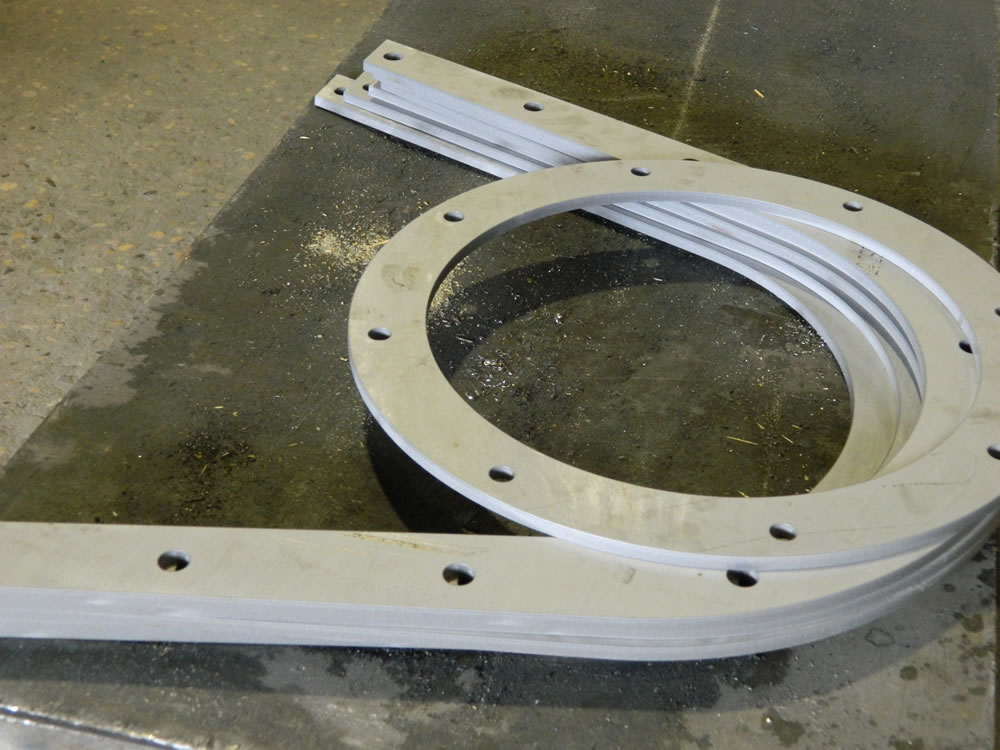 1/4 inch #304 stainless steel screw conveyor trough flanges and round inlet and discharge flanges. These parts go straight from the waterjet to welding.  Courtesy Anderson-Crane Company