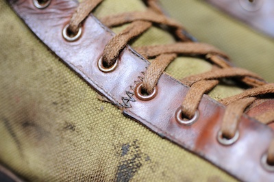 Detailed view of a pair of canvas and leather basketball shoes from the 1910s, showing the lacing, eyelets, stitching, and fabrication materials used.