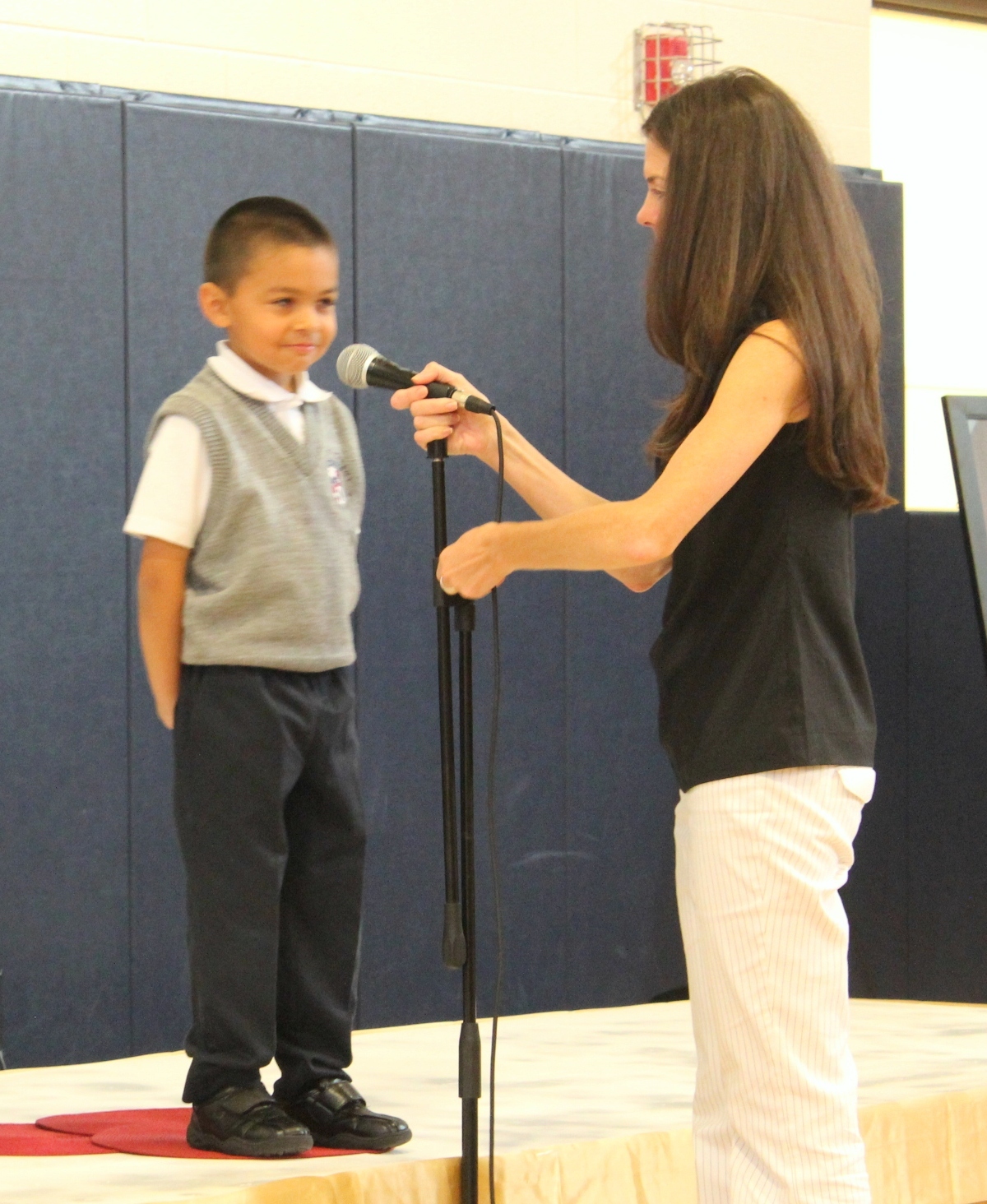 Dean of Students, Molly Maher, adjusts the microphone in order to capture Jean-Eduard's infliction and annunciation in the delivery of his poem.