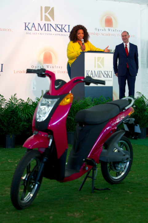 Oprah Winfrey on stage with Frank Kaminski, president and CEO of Kaminski Auctions, auctioning an autographed Jetson electric bike.