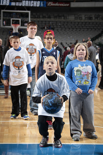 Children making a shot on the basketball court after the Mavericks game during the “One Shot Away” event.