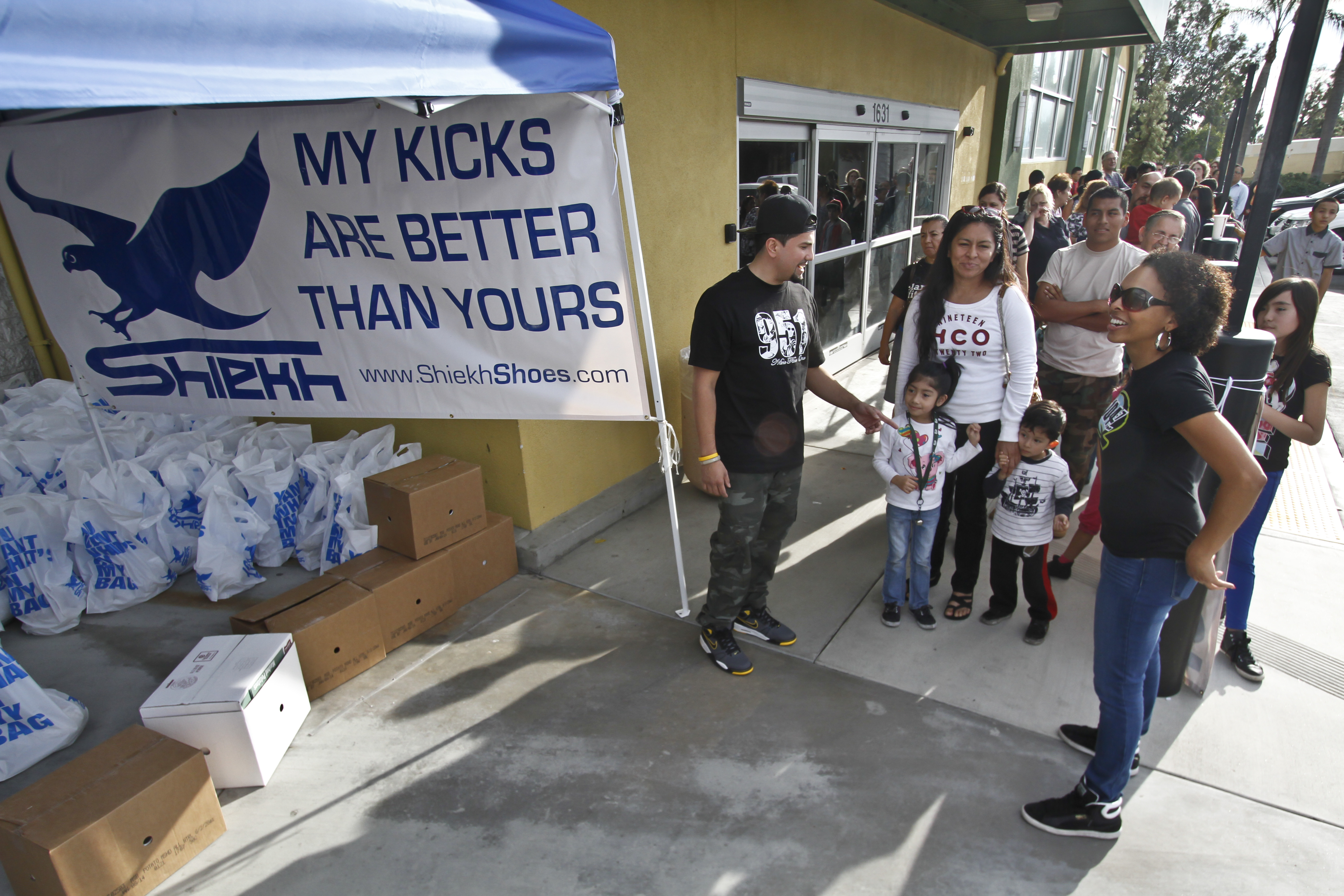 Families line up to receive turkey dinners at Shiekh Shoes on East Highland Avenue in San Bernardino on Tuesday during the second annual Thanksgiving Giveback. About 150 dinners were donated.