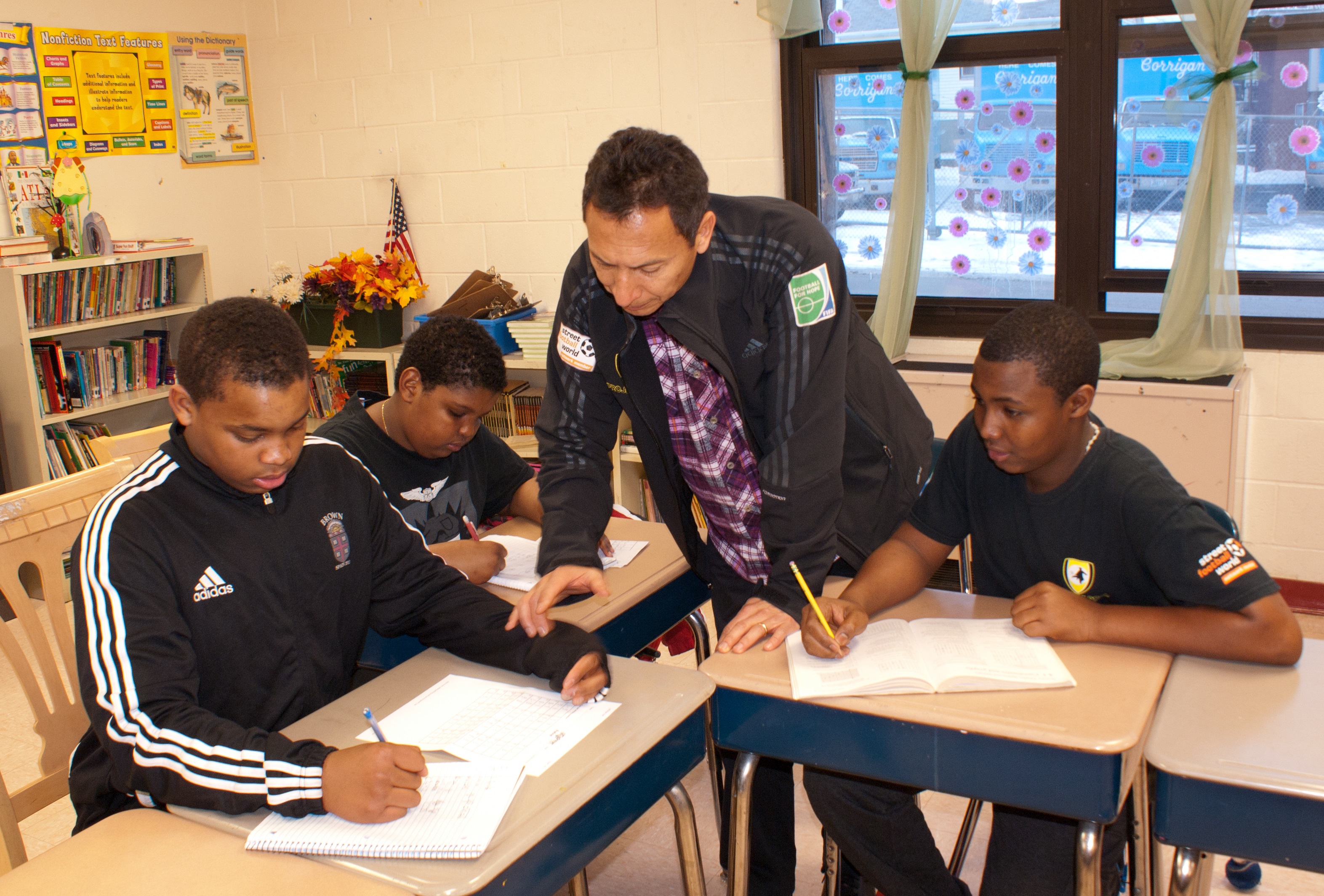 Project GOAL instructor Javier Gallego (center) assists Calcutt Middle School students Kevin Moreira. (left) and Junior Varela. with math homework. Also pictured (background) is Evanilson Gomes., anot