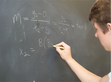 A student works out a mathematical problem on the blackboard at this private school in Northridge.