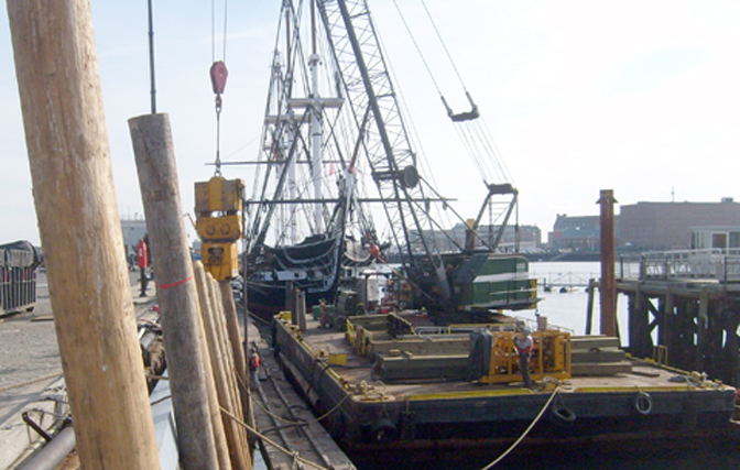C. White Marine is installing timber fender piles at the Charlestown Naval Shipyard in Charlestown, Massachusetts where the USS Constitution, “Old Ironsides” is berthed.