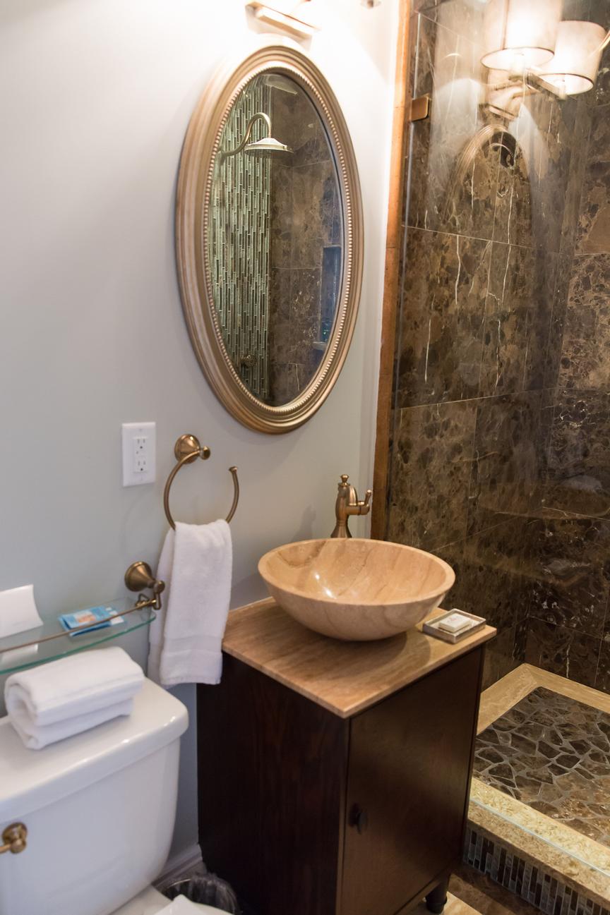 The private bathroom offers a tiled shower with body jets, as well as a vessel sink and vanity.