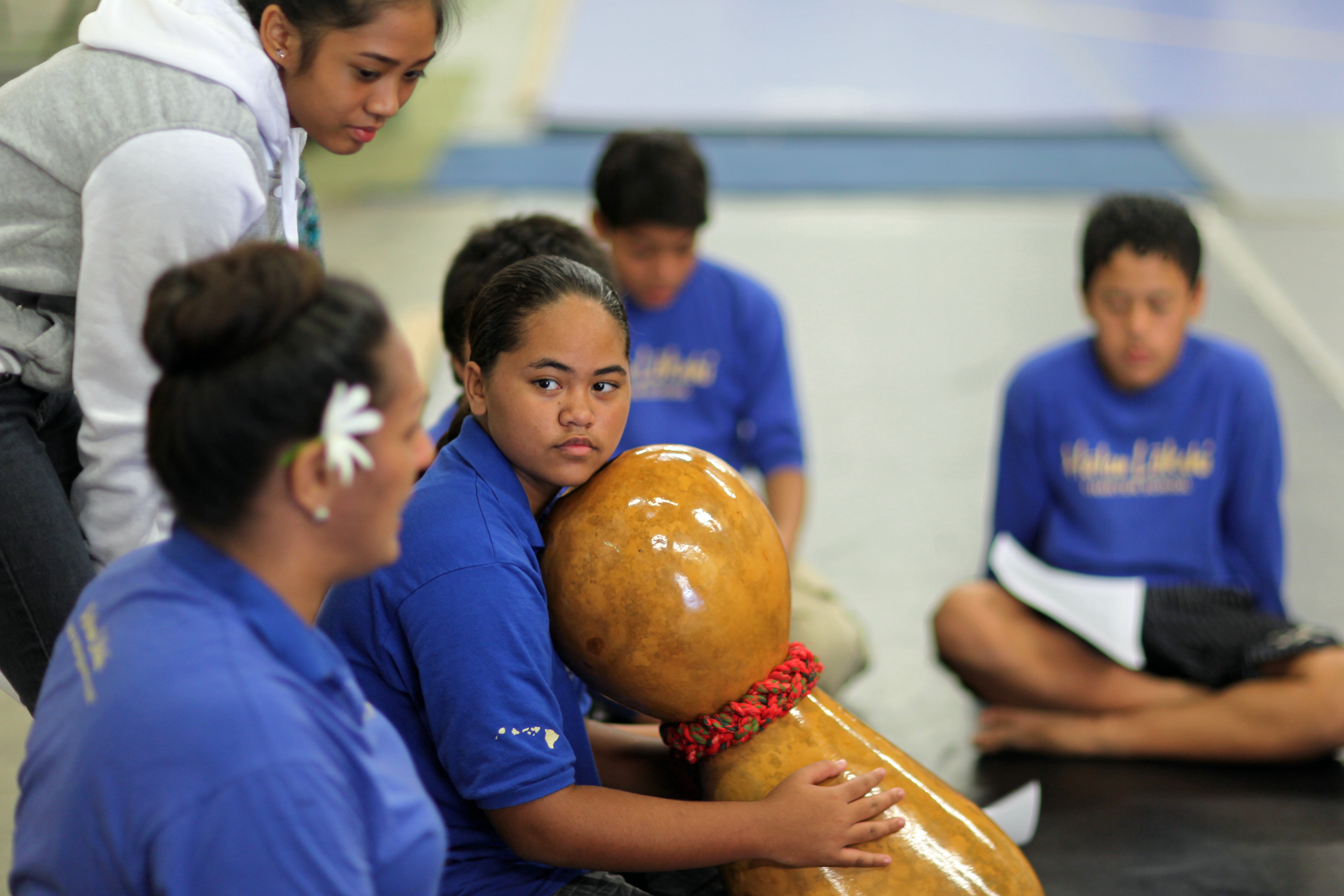 Kumu Hina mentoring Ho‘onani while other students watch.