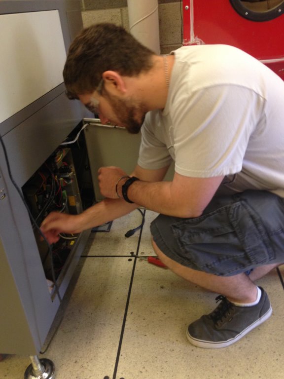 STEM student Ryan Seggerman performs electrical maintenance on a laser cutter in the Rocklin High School technology lab supported by the Sierra College STEM Collaborative.