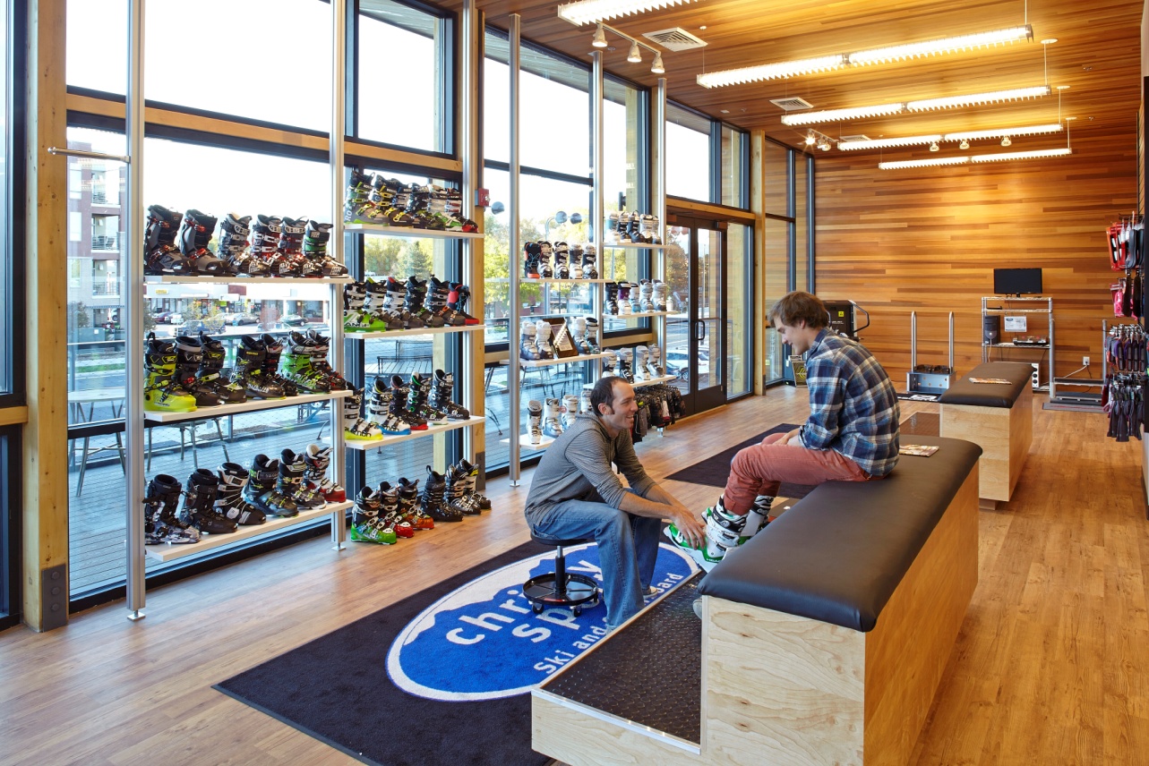 Wood-tone interiors and shelves backed by floor-to-ceiling windows highlight Christy Sports’ ski merchandise in Arch11 store renovation. (Photo: Arch11)