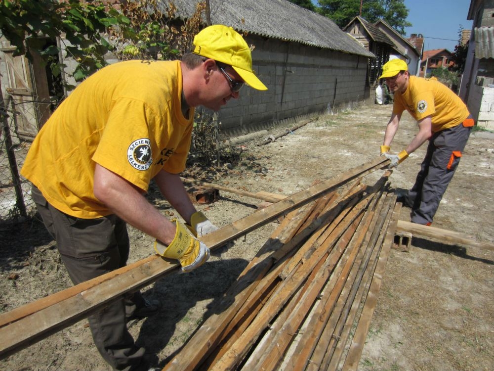 Scientology Volunteer Ministers stack beams salvaged from a condemned home in the village of Kopanica, in Bosnia and Herzegovina. These can be used to help the family rebuild their home.