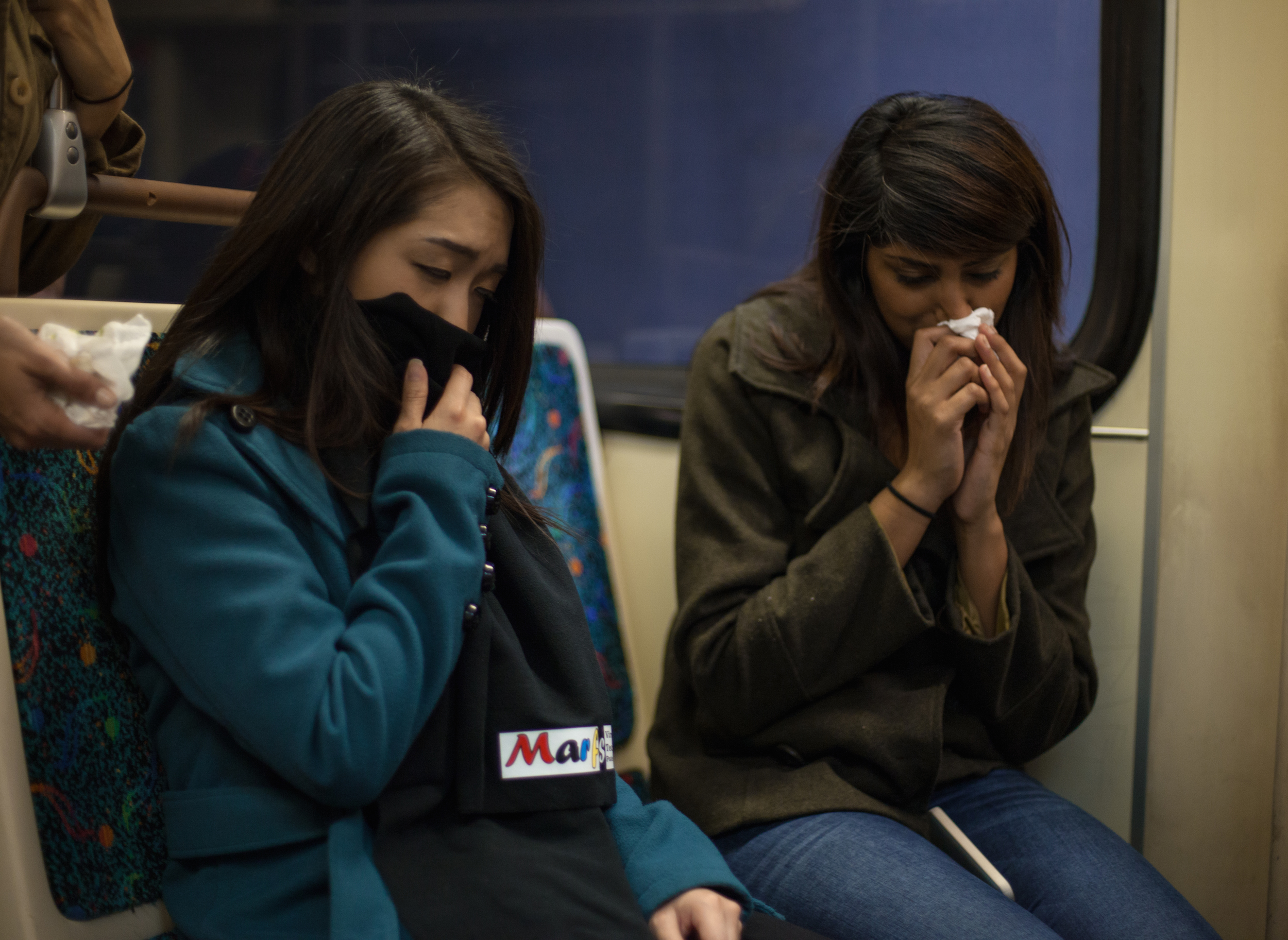 A woman covering her nose and mouth with her Marf after another commuter sneezed.