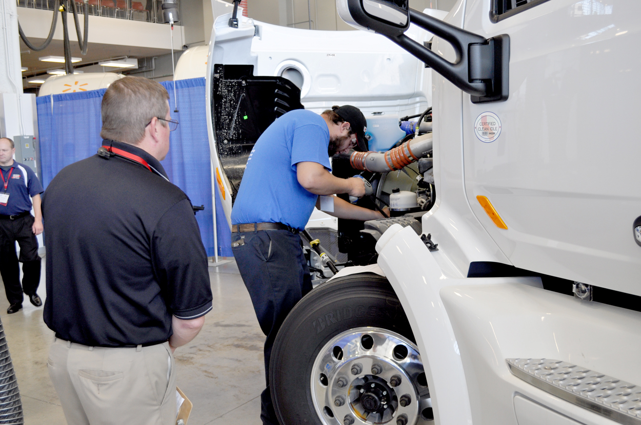 A competitor investigates a bug on a brand new Peterbilt truck on the HVAC station