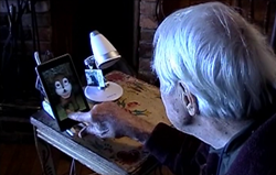 Photo of an older adult with Alzheimer's engaging with a GeriJoy caregiver through a tablet-based avatar.