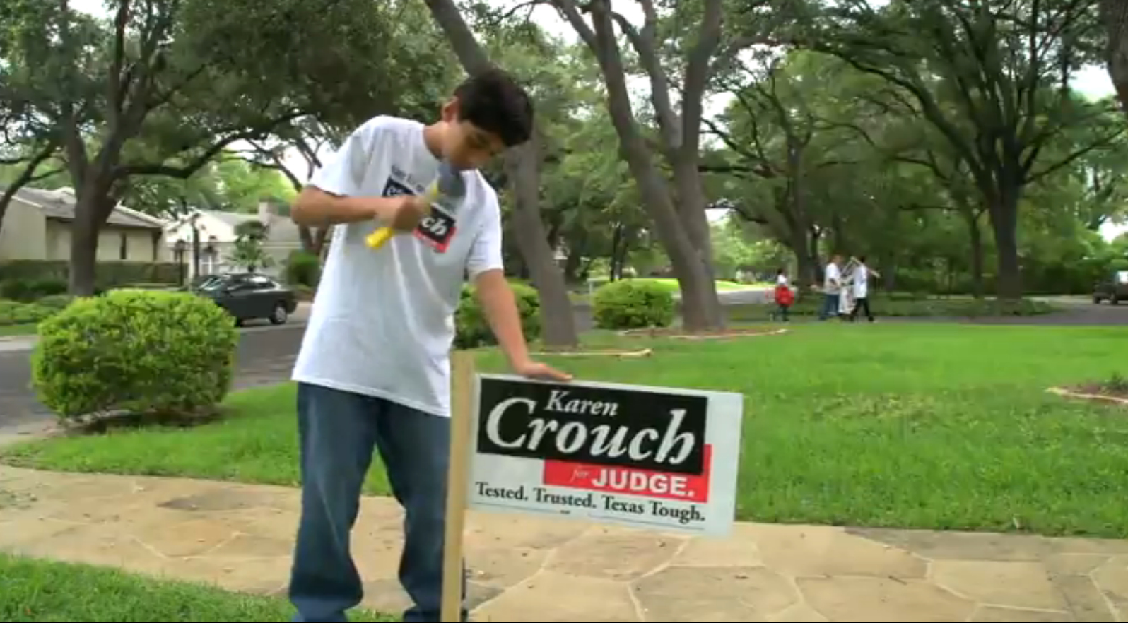 Son Nicholas Flores posts a campaign sign while his brother, sister and father blockwalk the neighborhood.