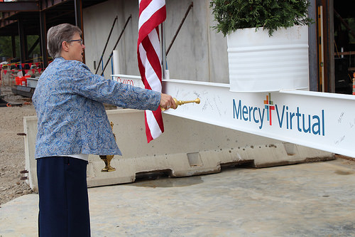 Sister of Mercy Claudia Ward blesses the final beam before it is hoisted into place.