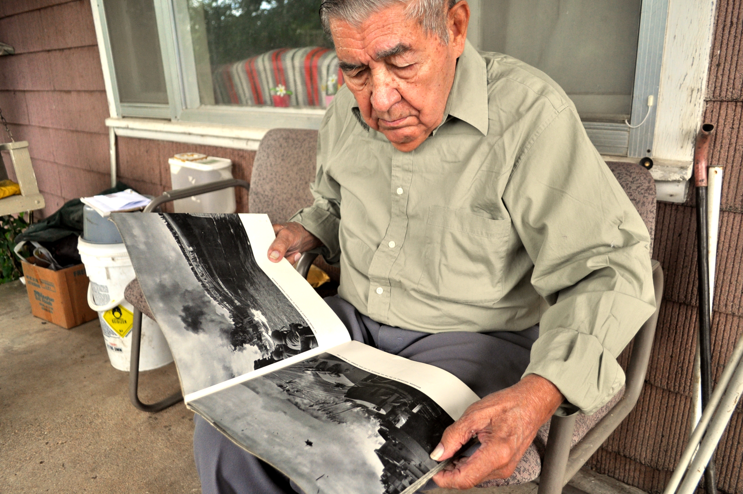 Cherokee citizen and World War II veteran Steve Downing Jr., of Locust Grove, recalls his years aboard the USS Santa Fe, as pictured in the book he holds.