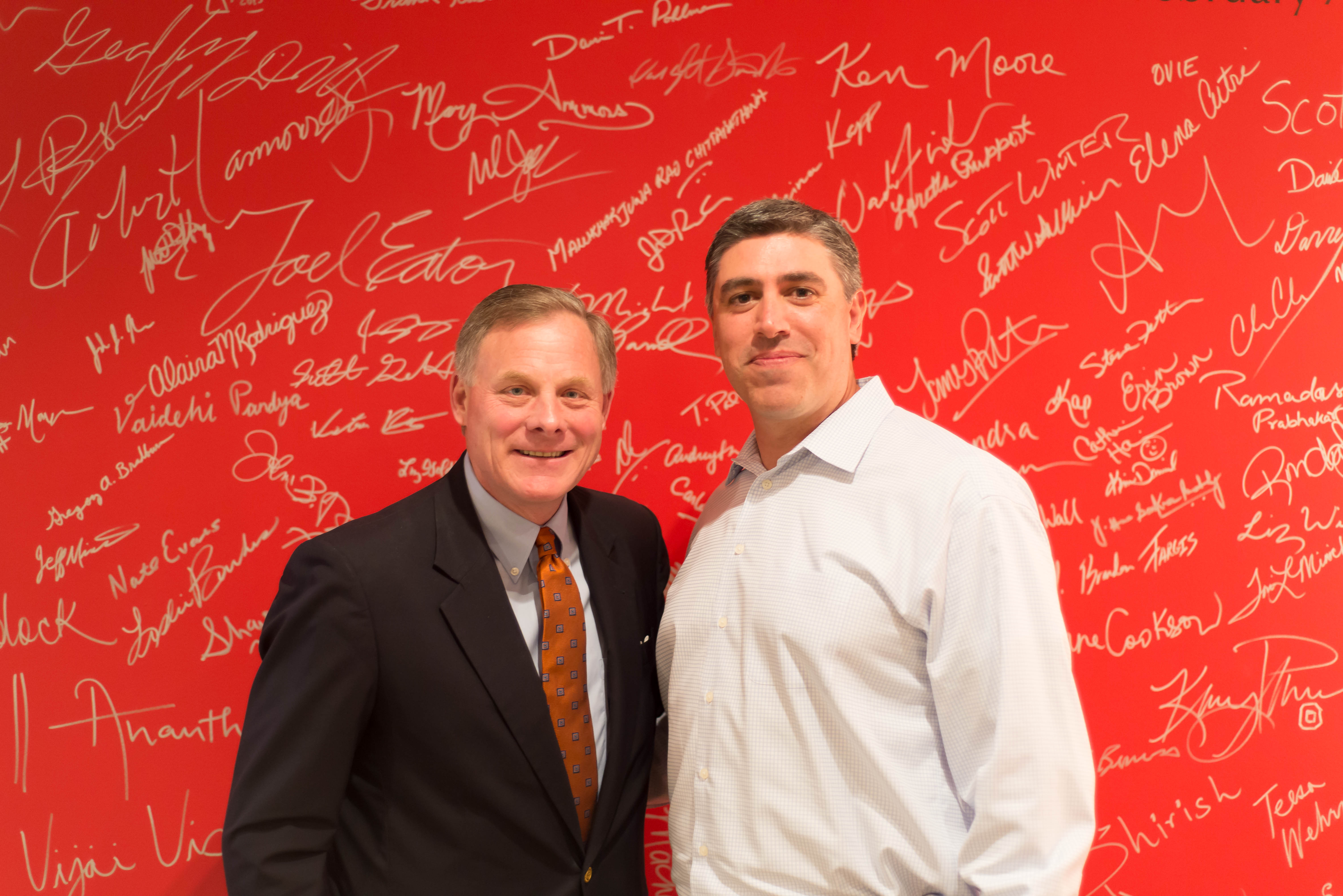 Mike Lipps poses with Sen. Richard Burr in front of the "People Wall" at the LexisNexis software business headquarters.