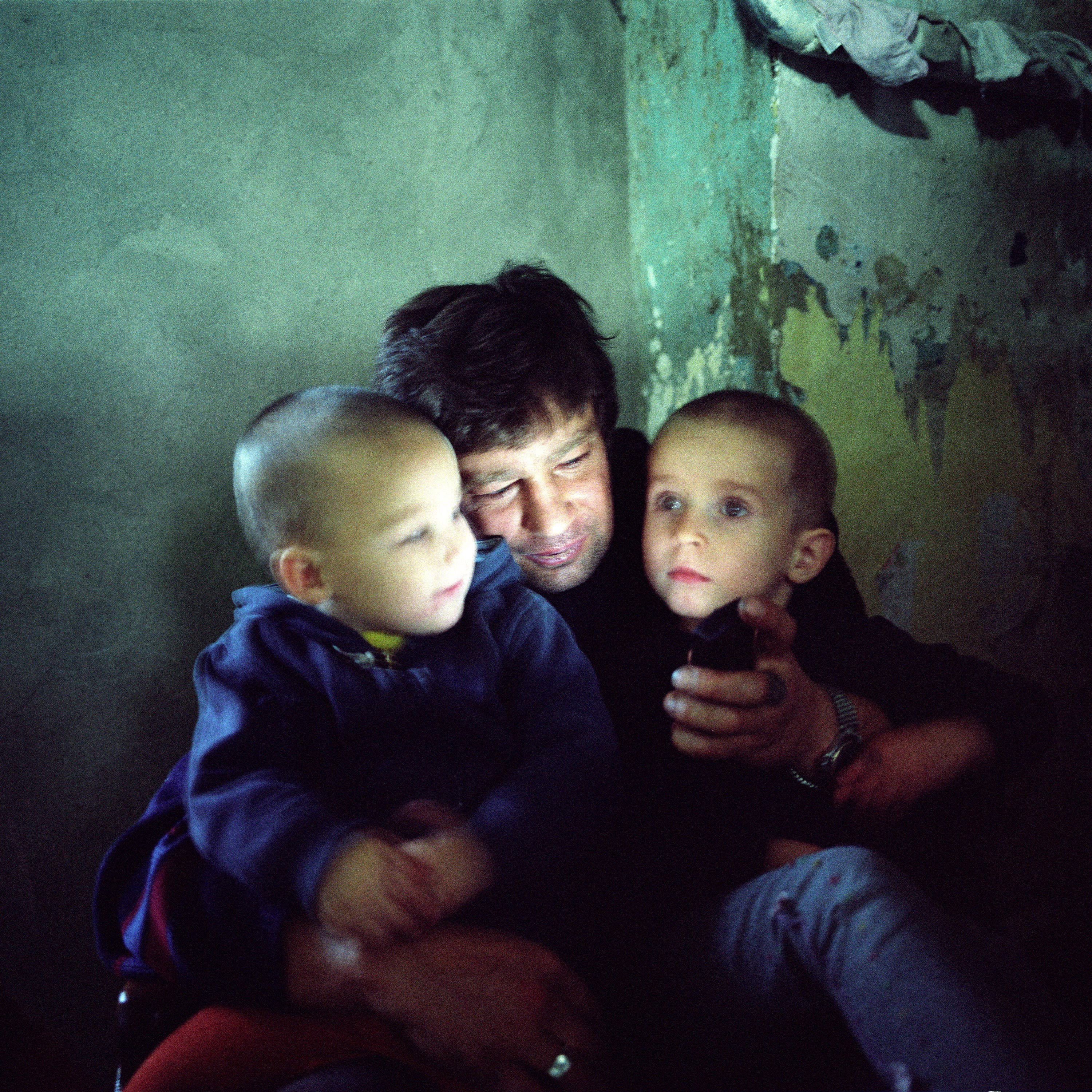 Sasha, who is HIV-positive, watches a video on his mobile phone with his child and grandson. Odesa, Ukraine, 2008. ©Joseph Sywenkyj