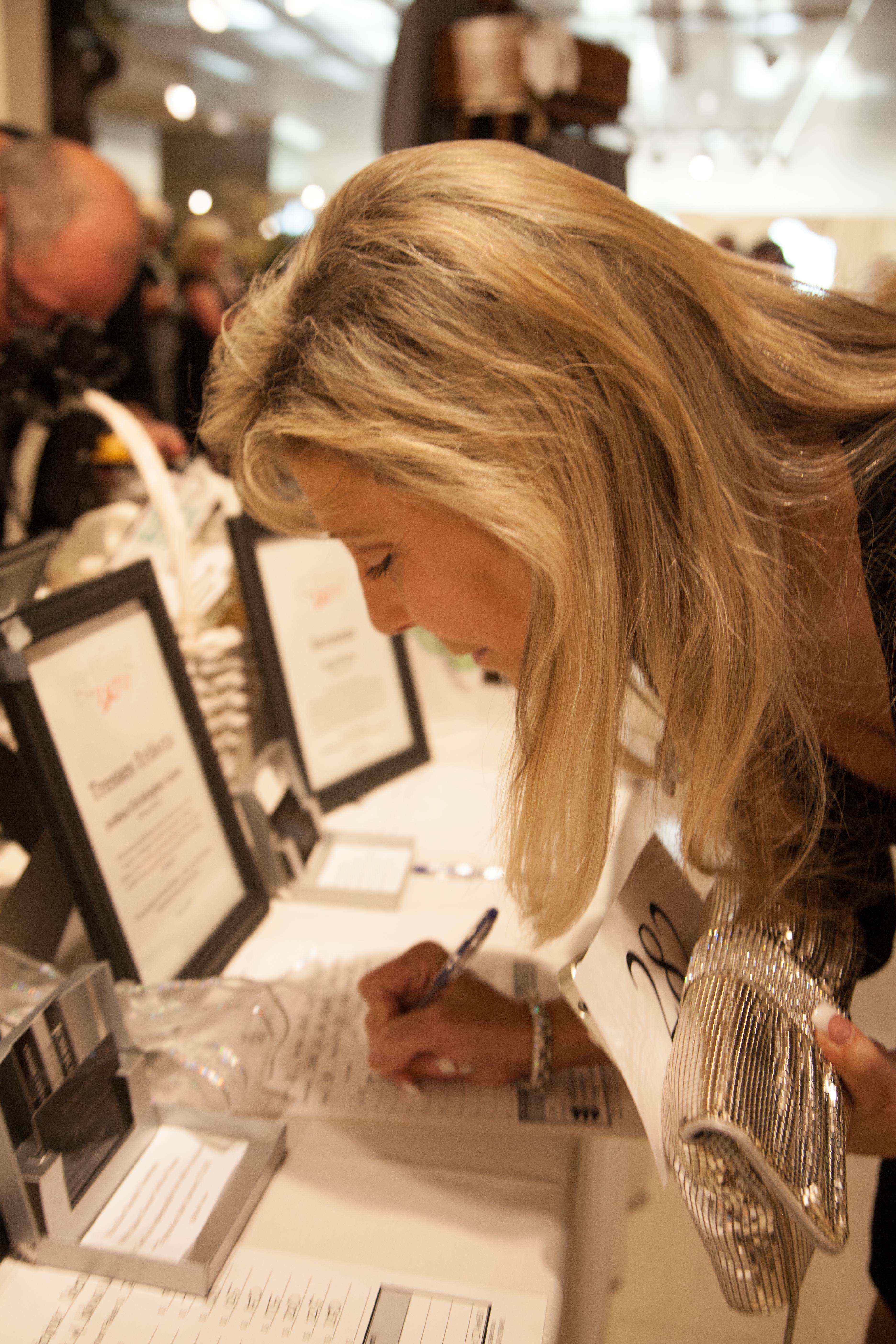 Diana Sabatino, Owner of DIANA & Company Jewelry Designs and one of Riviera Magazine’s Dynamic Women of Orange County, securing a silent auction item at "Getting to Zero" Fundraiser