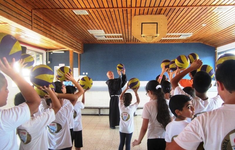 Fr. Quirico Calella, OFM, Director of the Terra Santa School in Acre, shows children how to correctly shoot a basketball.