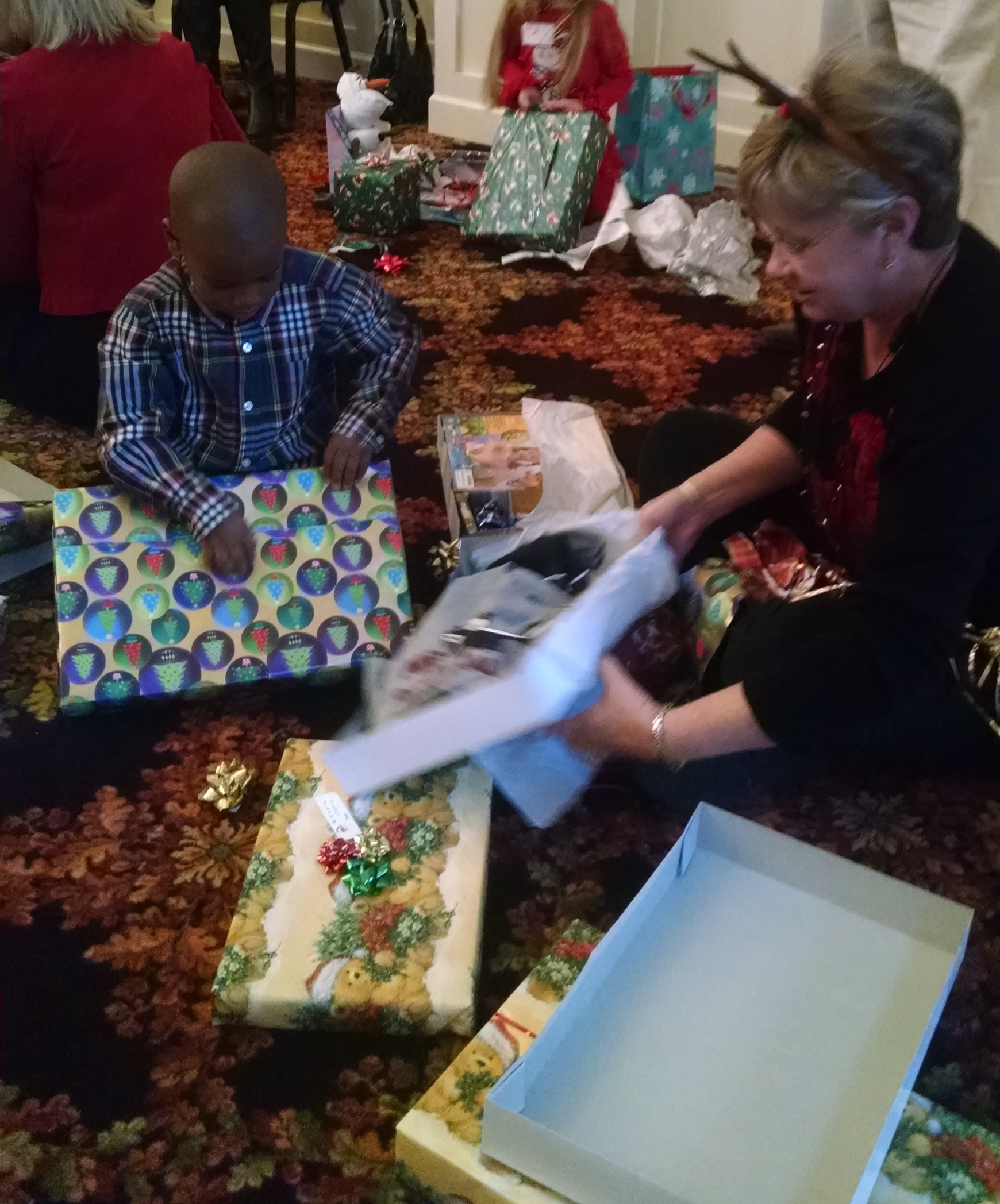 Abernethy Laurels Resident Barbara Murray helping children open their gifts.