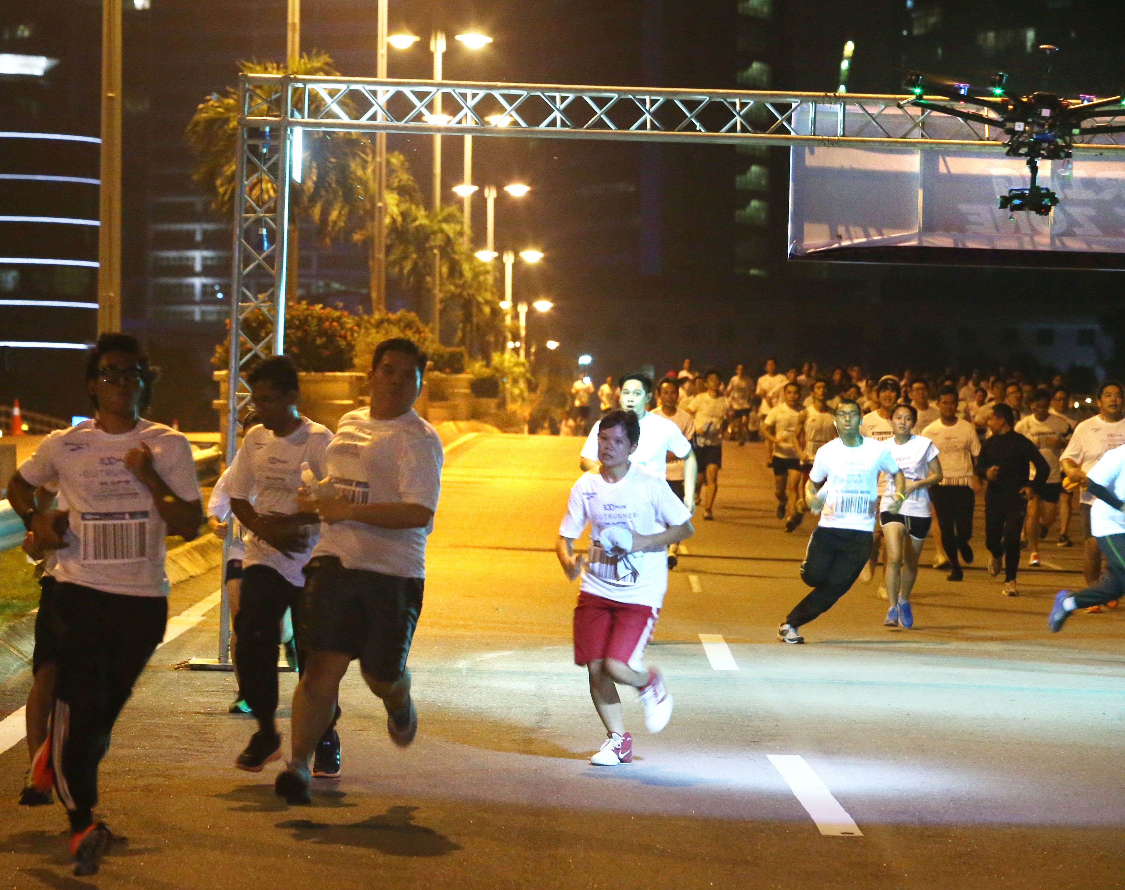 Participants in the 100PLUS Outrunner Race Against the Machines (RATM) 6km fun run avoiding a drone (top right) during the race.