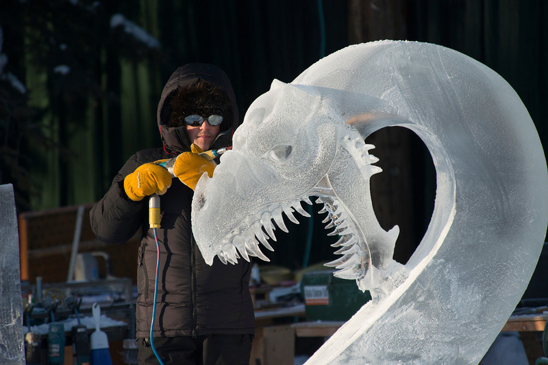 Steve Brice carves a dragon head from a block of ice. (Photo by Sherman Hogue/Explore Fairbanks)