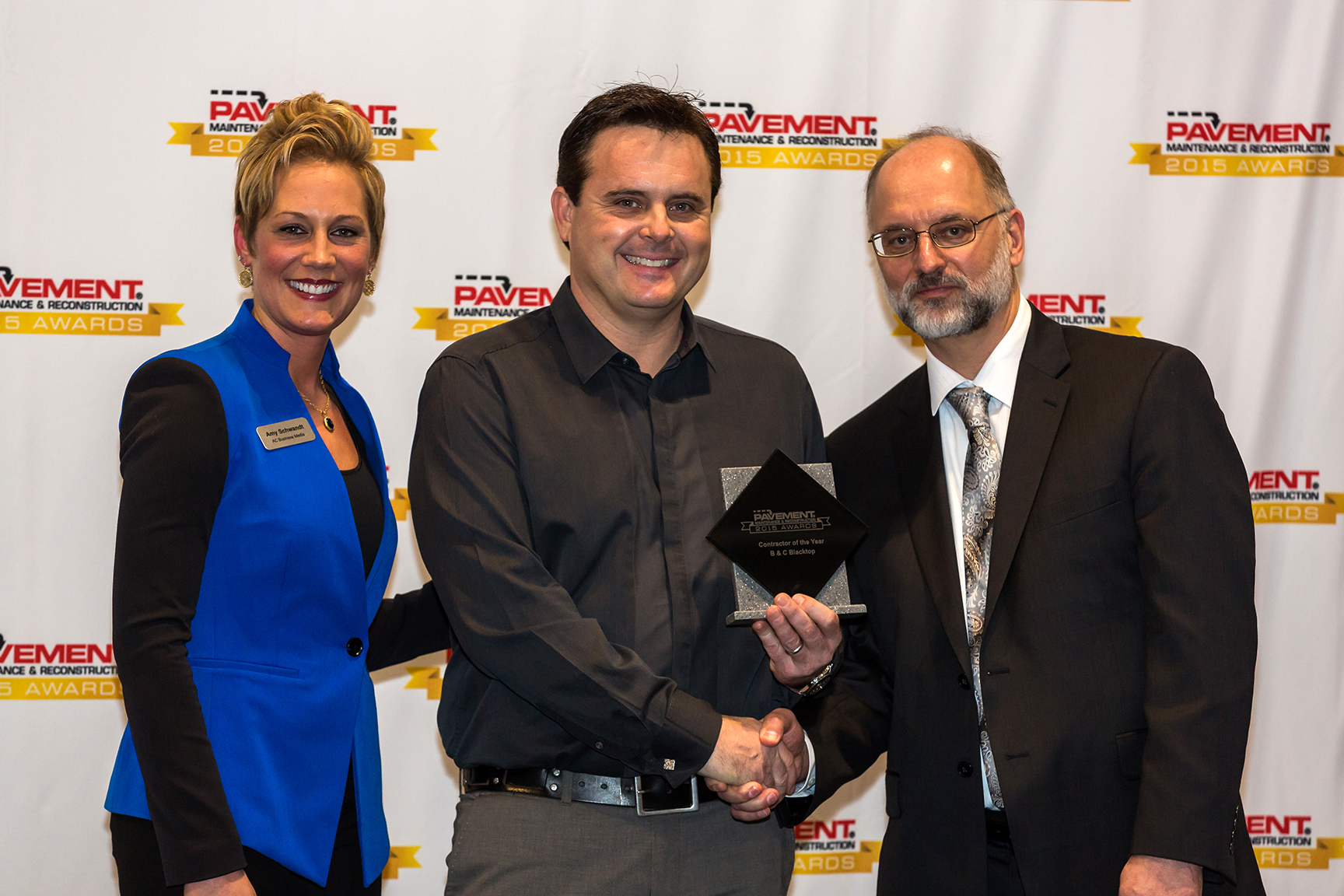 Bryan Myers (center), B & C Blacktop in Columbus, Ohio, receives the 2015 Contractor of the Year Award during the Pavement Awards ceremony from Amy Schwandt (left), show manager of National Pavement E