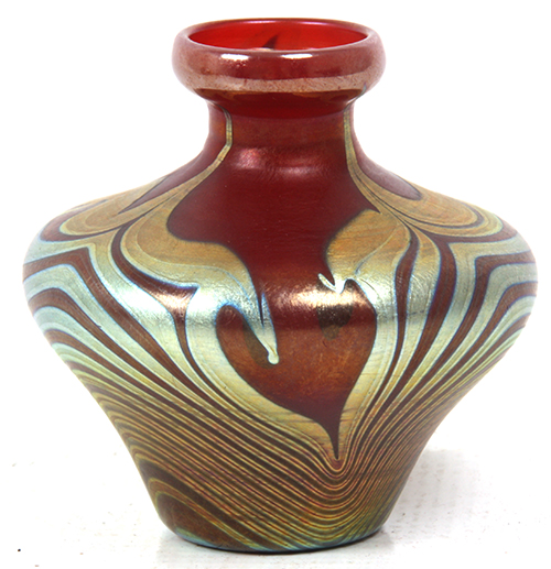 Lot 178: Tiffany Studios Favrile deep red hooked feather vase with tapered body, 3 ¼ inches in height.