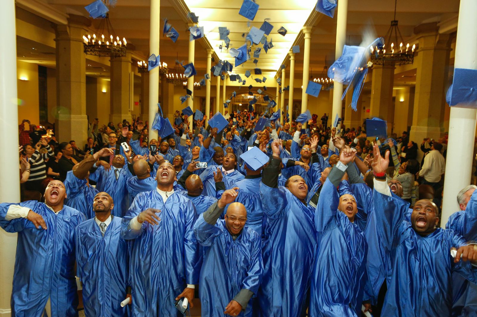 Graduates of The Doe Fund's Ready, Willing & Able transitional work program toss their caps in celebration