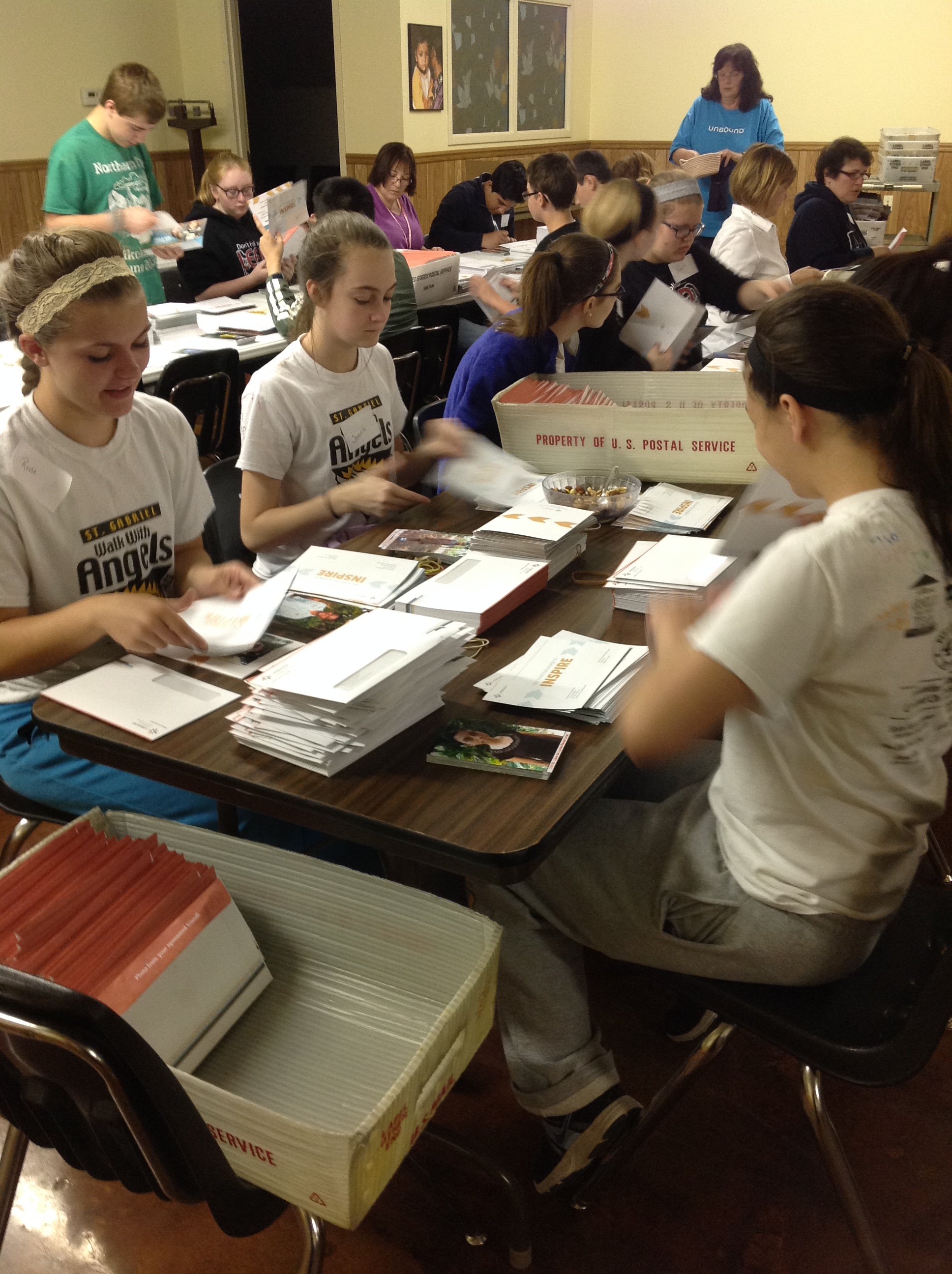 Students from St. Gabriel Middle School volunteer at Unbound, stuffing letters to sponsors to get mailed out.
