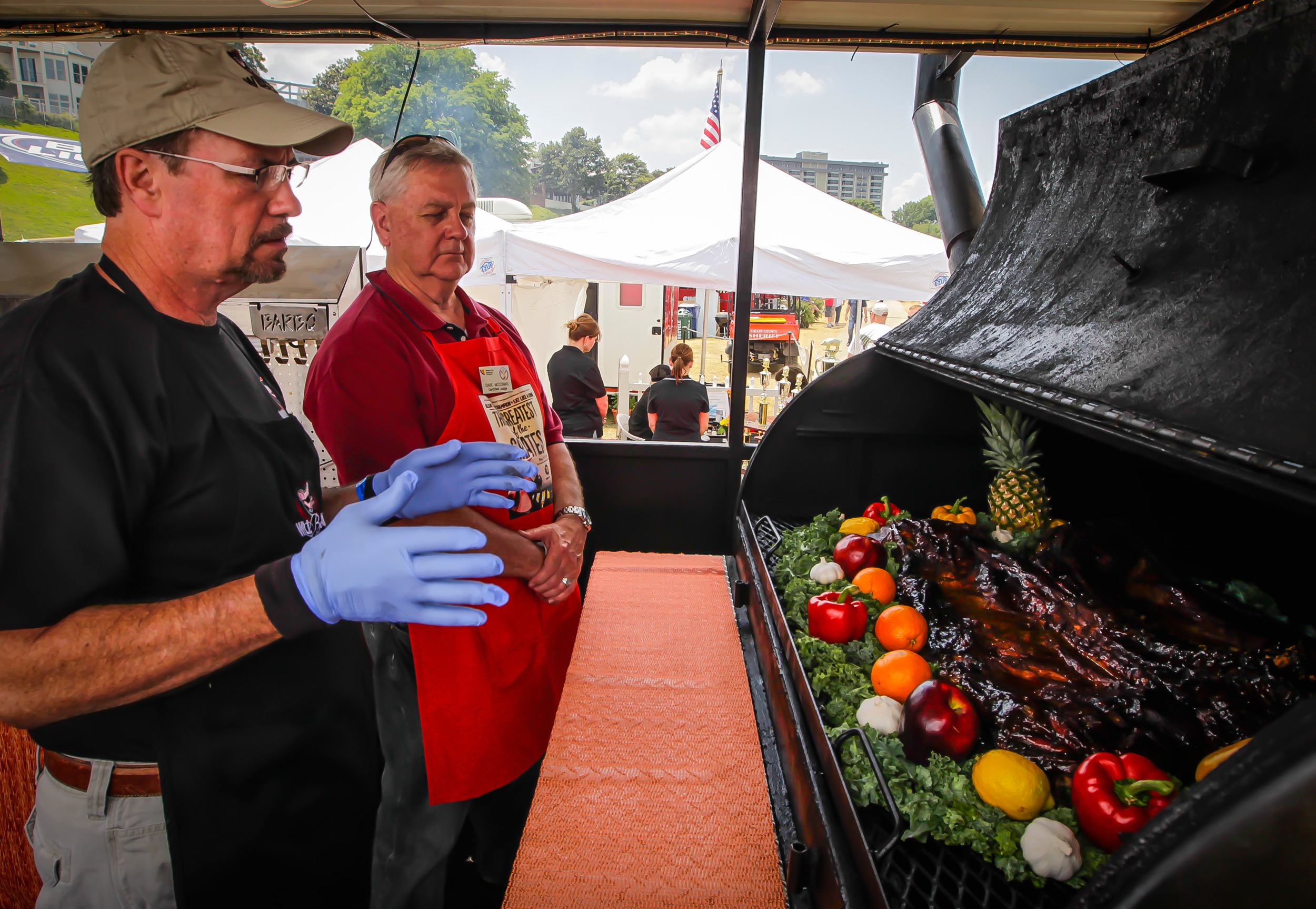 Barbecue competitor discusses his whole hog cooking method with a Memphis in May BBQ judge