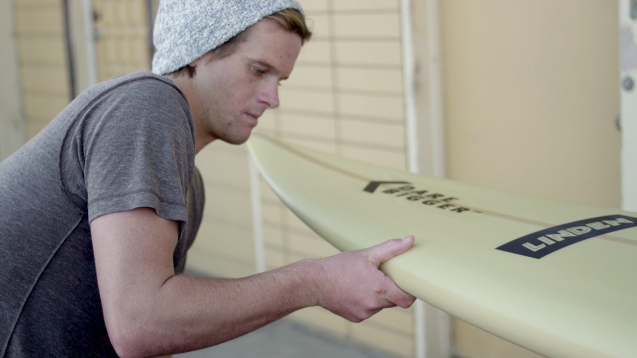 Professional Surfer Nic Lamb Examining a Big Wave Surfboard Featuring DuPont™ Kevlar®