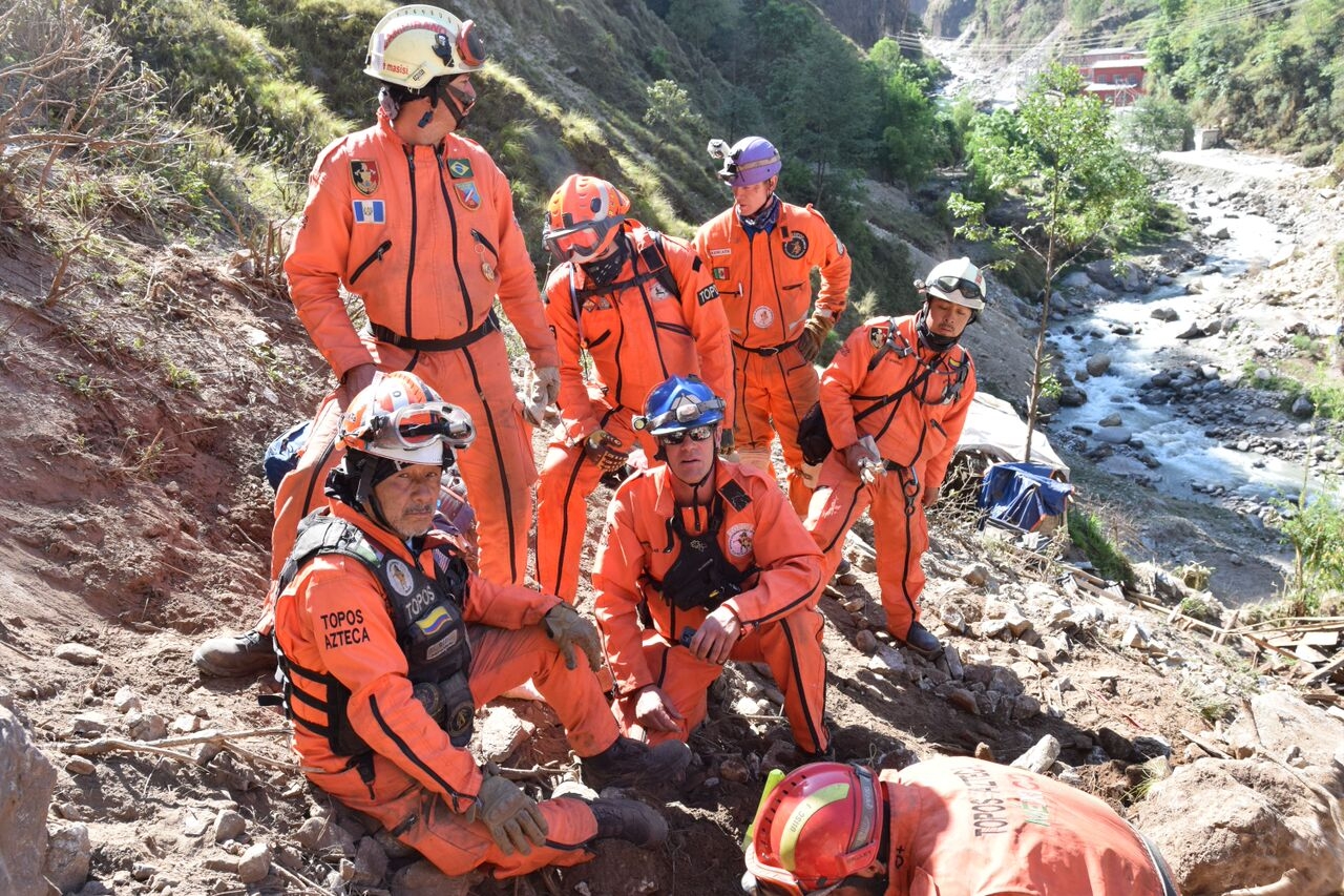Héctor Méndez, founder and president of Los Topos Aztecas (seated at the left) directs his team in searching for bodies buried in a ravine in the mountains in Nepal.