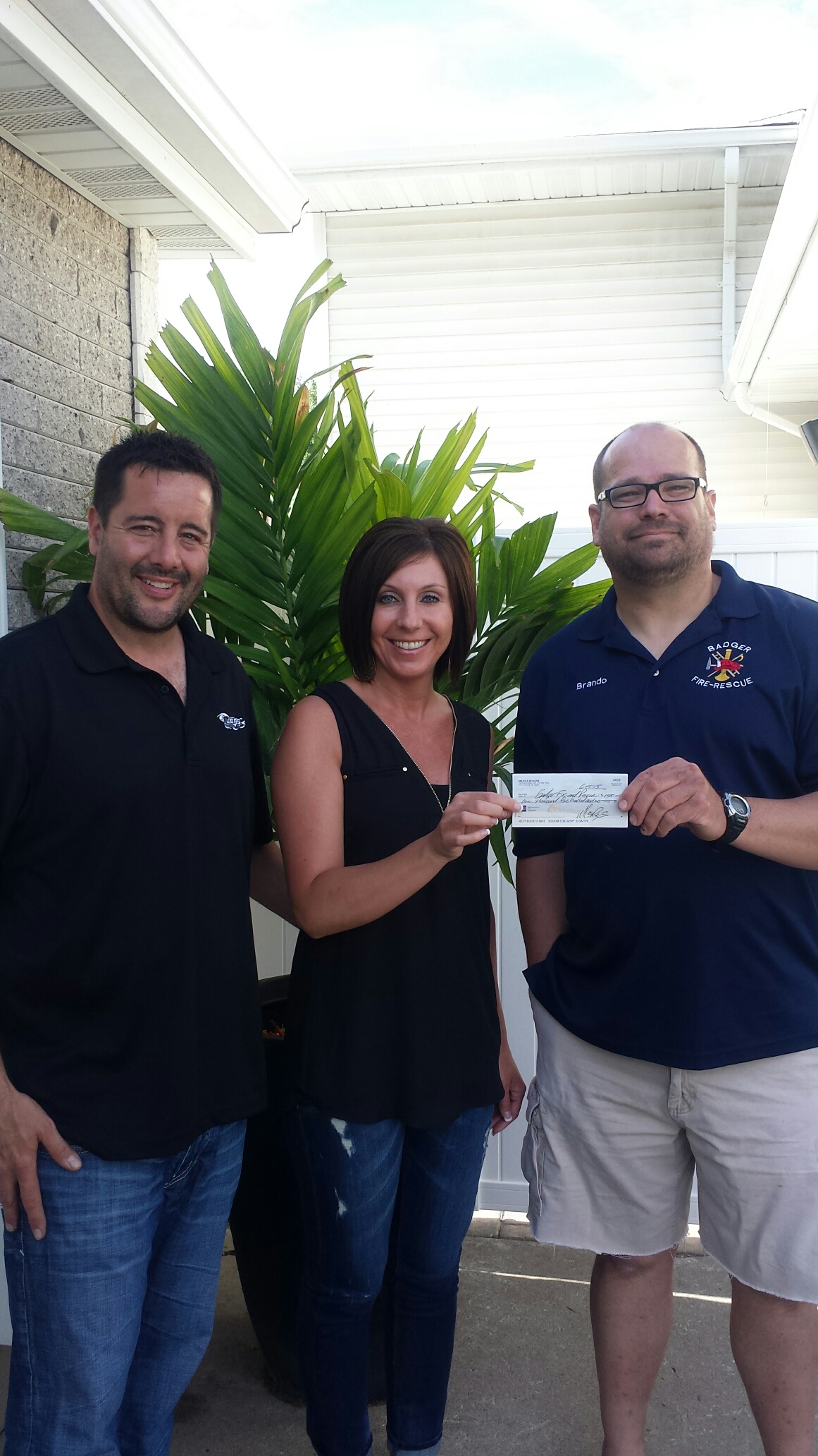 Miles and Laura from Rogers Tire giving check to Brandon Evans with the Badger Fire & Rescue