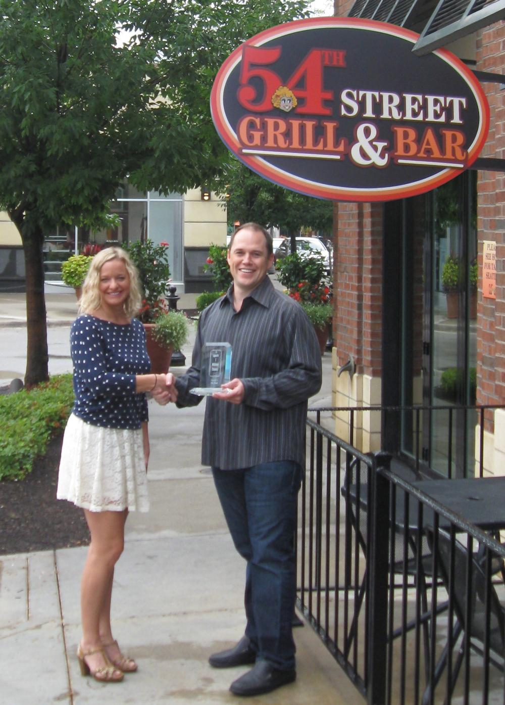 Chris Horsefield, Chief Technology Officer for Front Flip, presents 54th Street's Director of Marketing and Guest Relations, Kelly Reid, with a trophy commemorating the million-scan milestone
