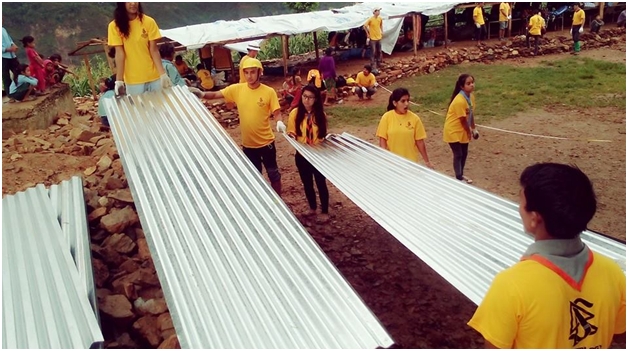 Volunteers place metal sheets to form the roof and walls of a shelter in a Nepal village.
