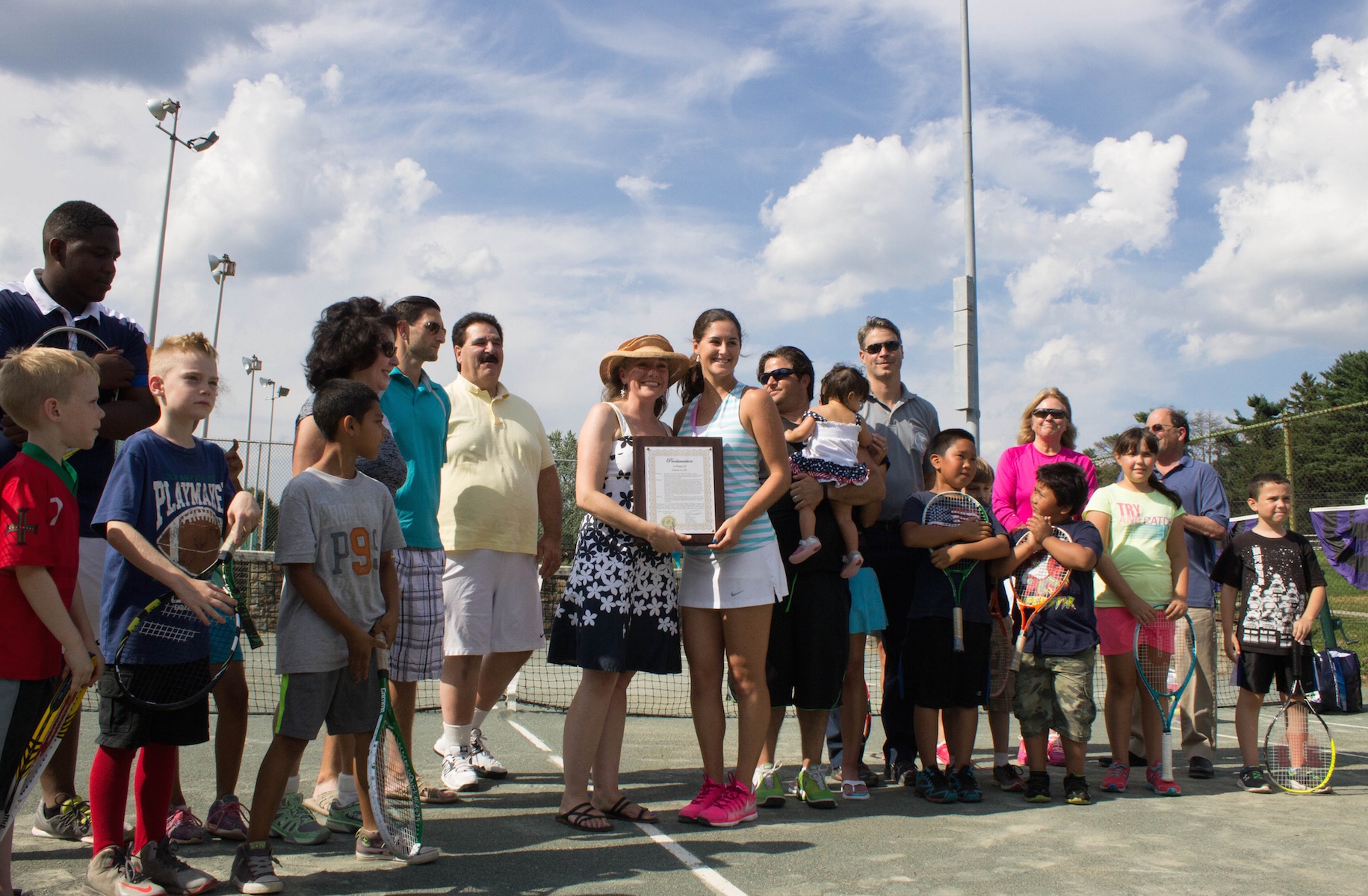 Jamie Loeb, NCAA Women’s Singles Tennis National Champion, receives a special proclamation from Village Mayor Victoria Gearity surrounded by family, friends and children from the Ossining Day Camp.