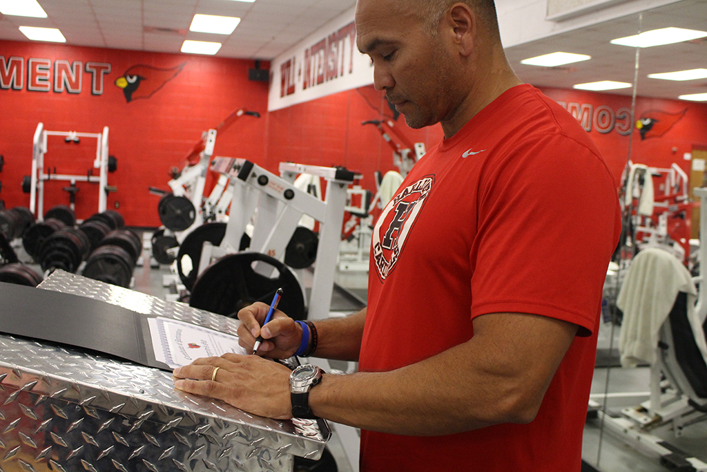 Head Football Coach, Manny Gomez, signing Harlingen High School Athletic Department's partnership with Integrity's Gift
