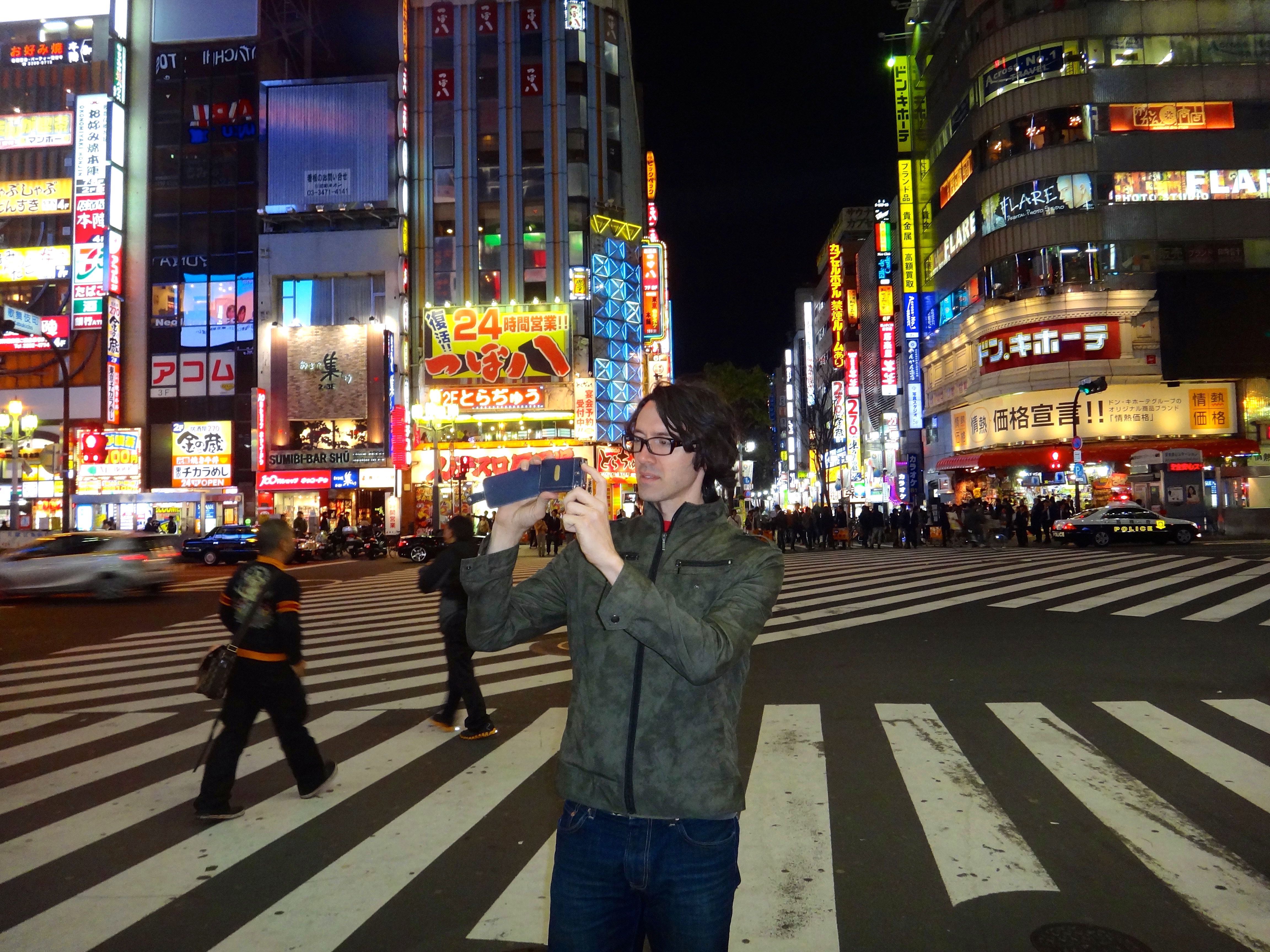 Tom (Jonathan Sherr) taking a photo in Tokyo