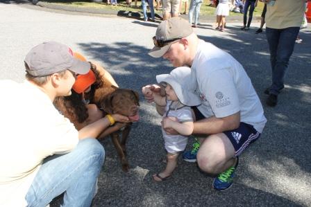 Parents David and Natalie Oliver and their baby make friends with “Piper” LoGrasso, a lab/pitbull mix (adopted through Adopt-A-Dog) at the 28th Annual Puttin’ on the Dog