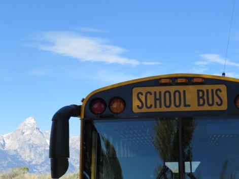 The Grand Teton is visible behind a school bus parked at Kelly Elementary School, bordering on the National Park and recently remodeled by Ward + Blake Architects of Jackson, Wyo.
