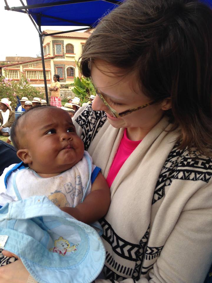 Edgar holding a baby while visiting Unbound's program in Madagascar.