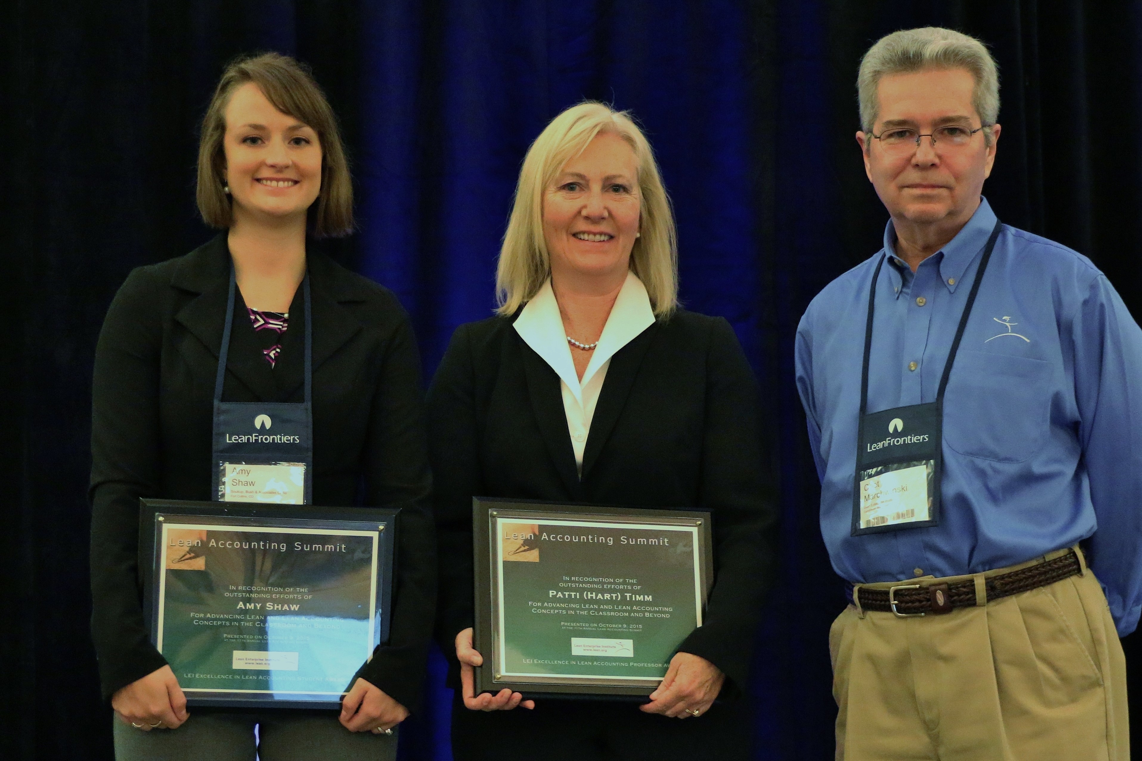 Amy Shaw, left, and Professor Patricia Hart Timm accept Excellence in Lean Accounting Awards from Chet Marchwinski, communications director, Lean Enterprise Institute.