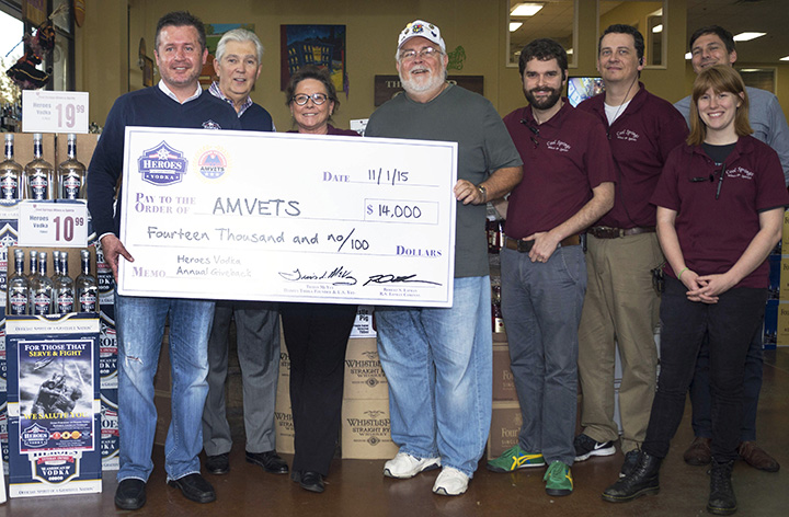 Travis McVey presents a $14,000 giveback check to AMVETS, accepted by the owner and staff members at Cool Springs Wines & Spirits.