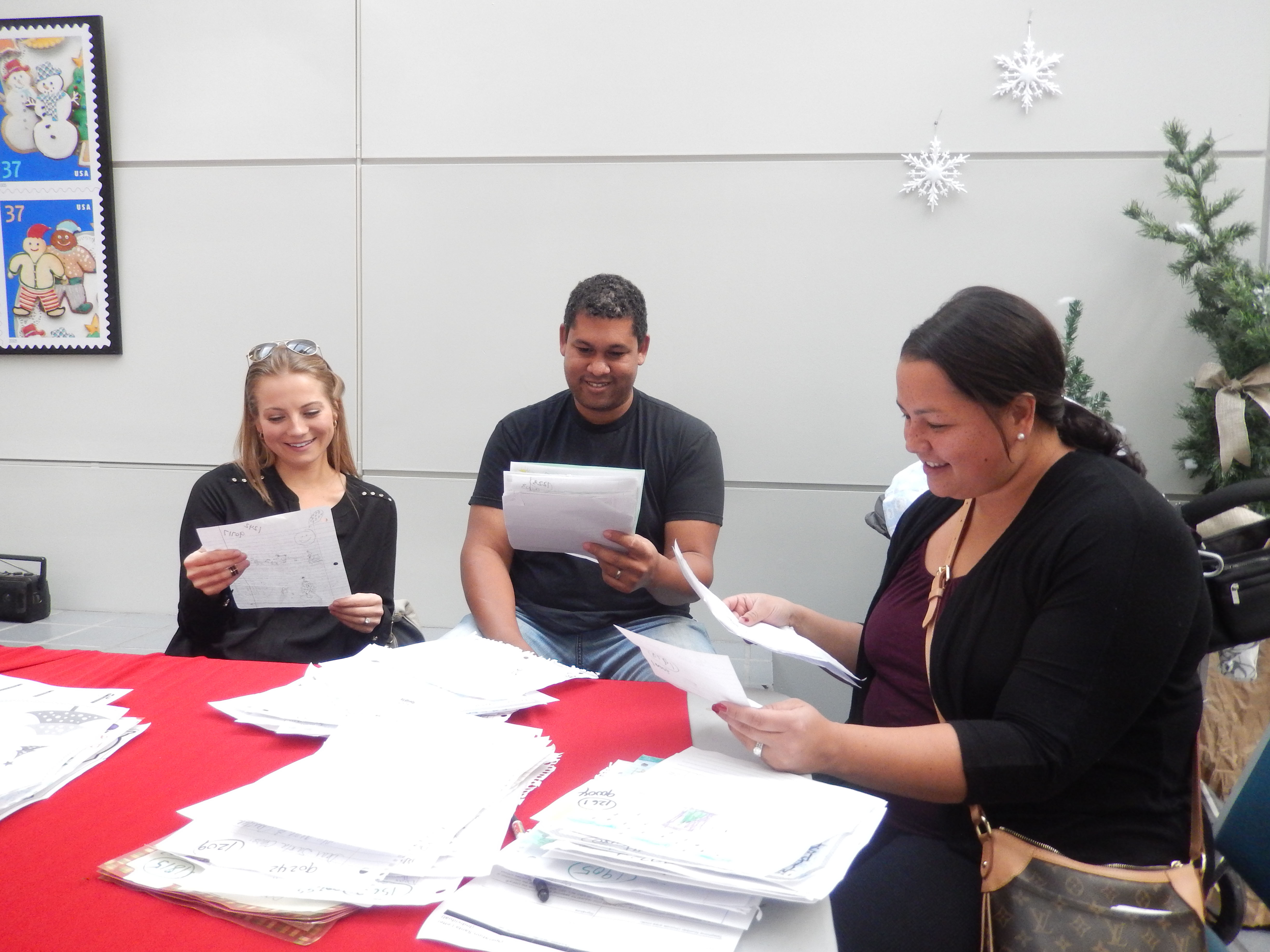 Volunteers for USPS Operation Letters to Santa reading letters in Los Angeles.