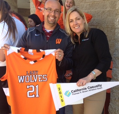 Woodland High School Basketball Coach Javier Marin and California Casualty's Tami Phillips show off the new girls basketball uniforms