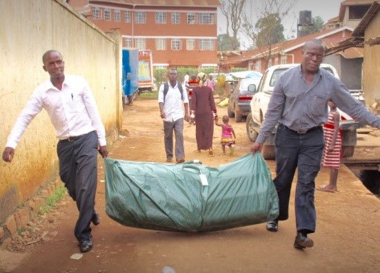 Relief Beds being carried into the Slum in Bwaise by volunteers.